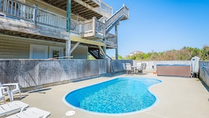 A swimming pool with a wooden deck, lounge chairs, and a hot tub. - Skyview by the Sea (Corolla)