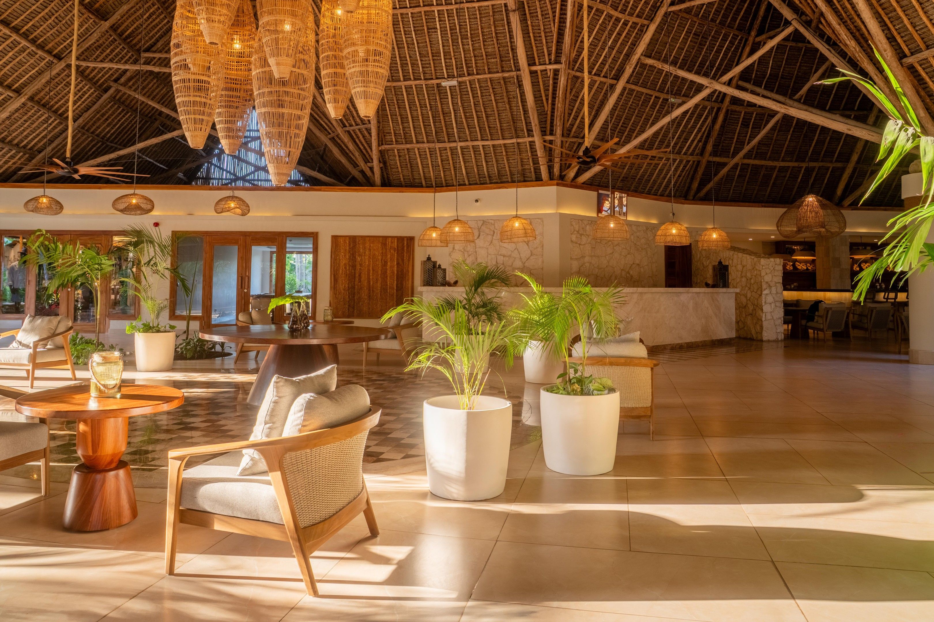 A spacious lobby with high ceilings, wicker furniture, and large potted plants.