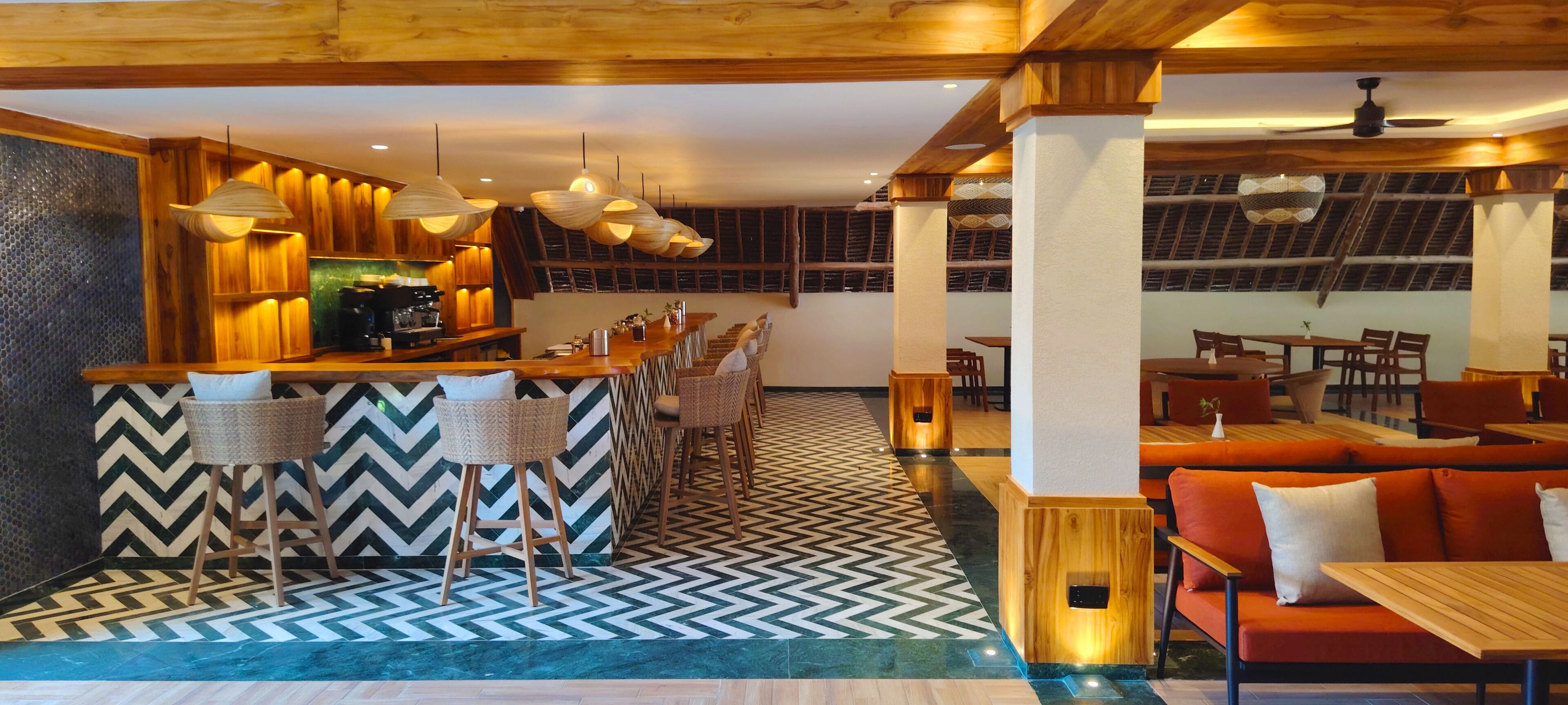 A restaurant with a bar area, wooden furniture, and patterned flooring.