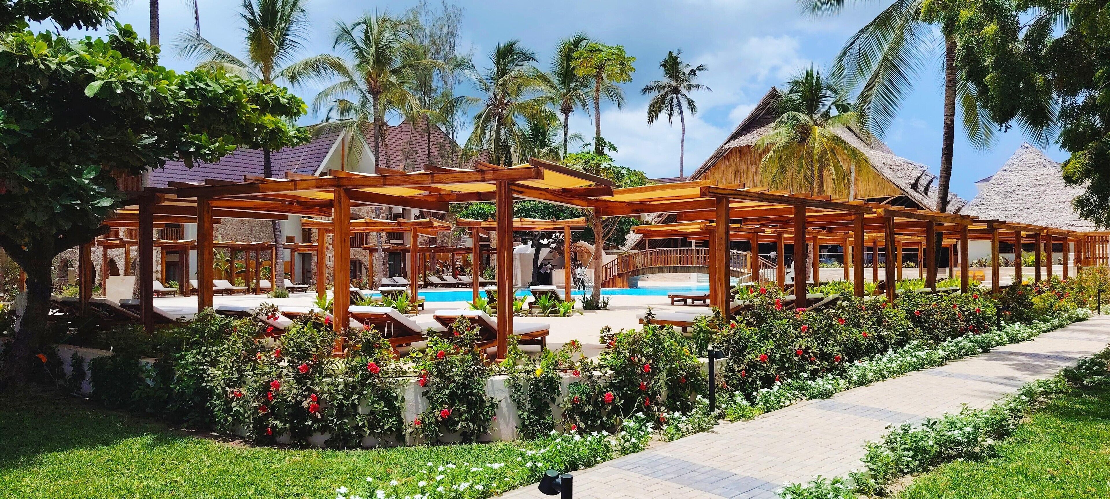 A resort with outdoor seating areas, a swimming pool, and lush greenery.