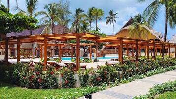 A resort with outdoor seating areas, a swimming pool, and lush greenery.