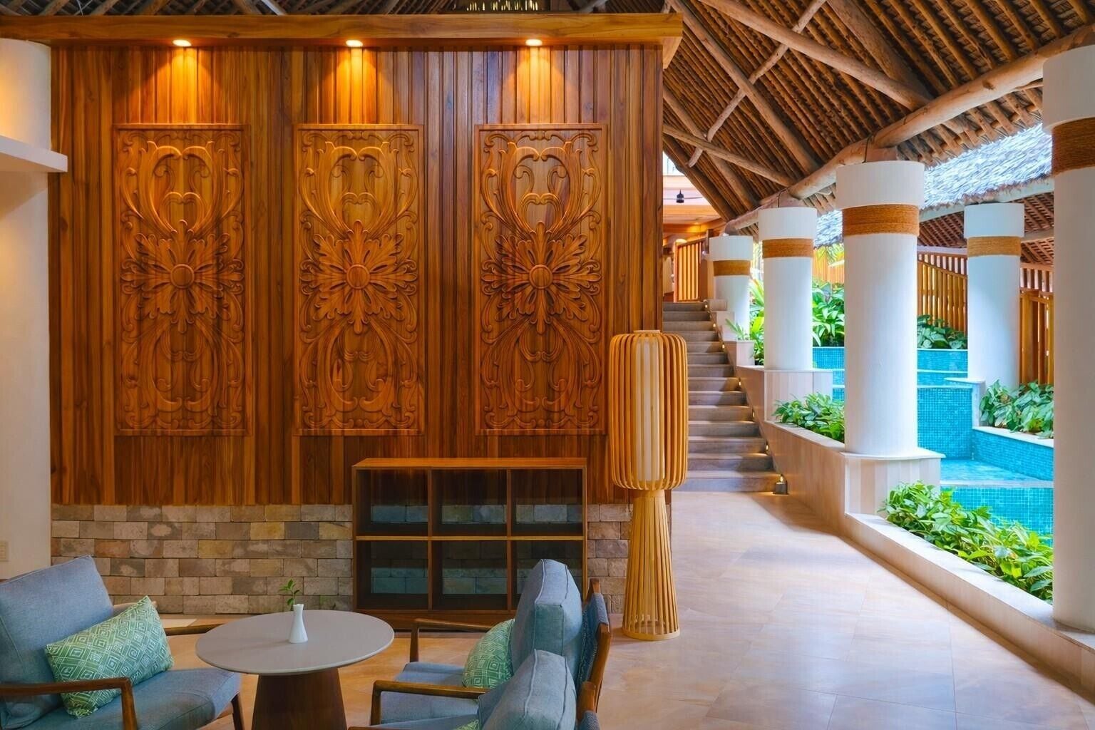 A hotel lobby with a stone fireplace, seating area, and a view of a pool.