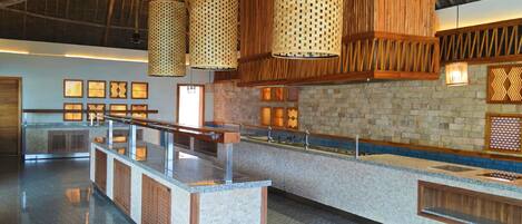 A spacious kitchen with a long counter, hanging woven light fixtures, and a brick wall.