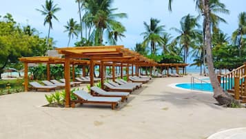 A resort with wooden pergolas, lounge chairs, and a pool.