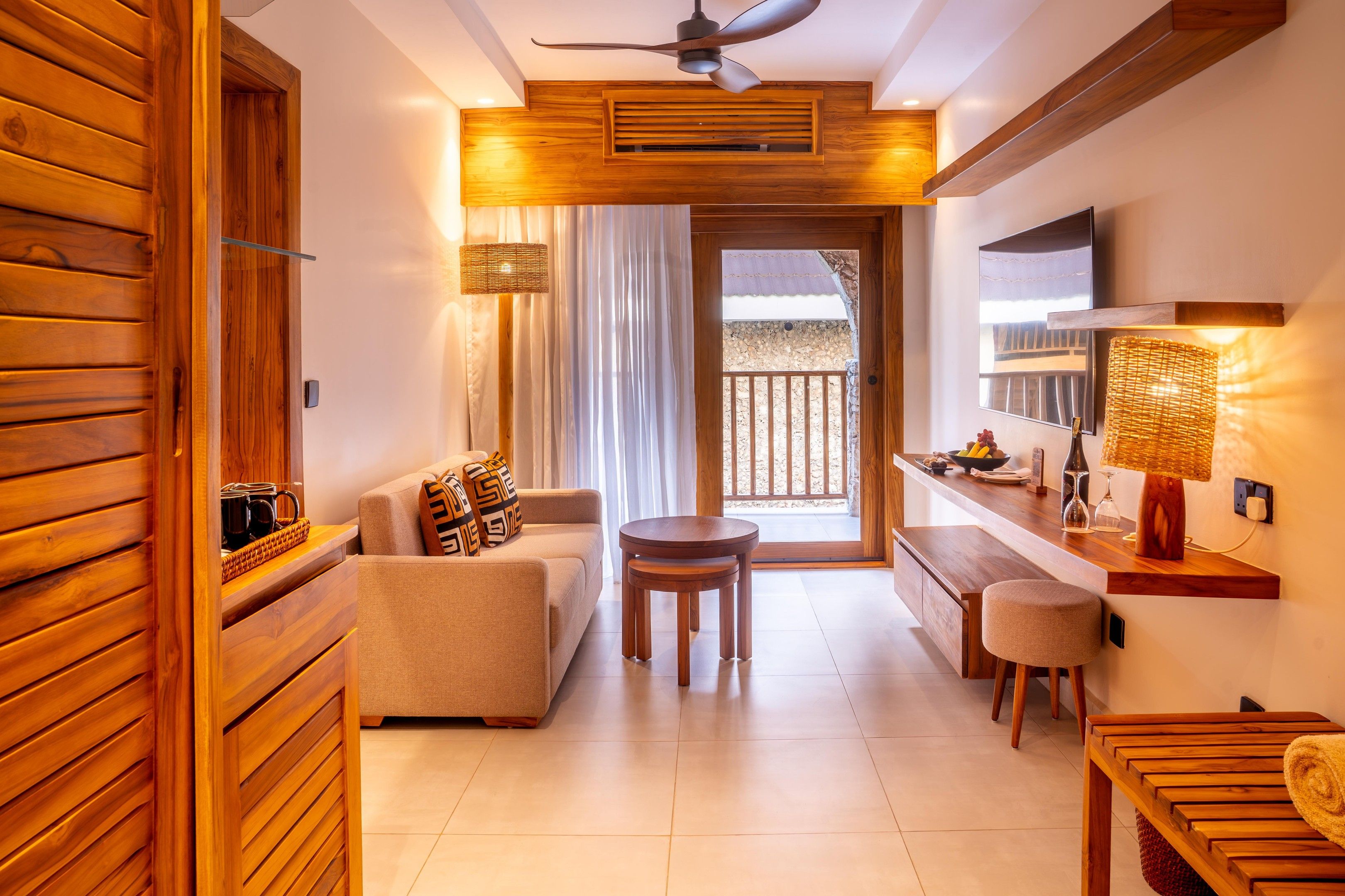 A modern interior with a wooden accent wall, a sofa, a small table, and a kitchen area with a counter and a hanging lamp.
