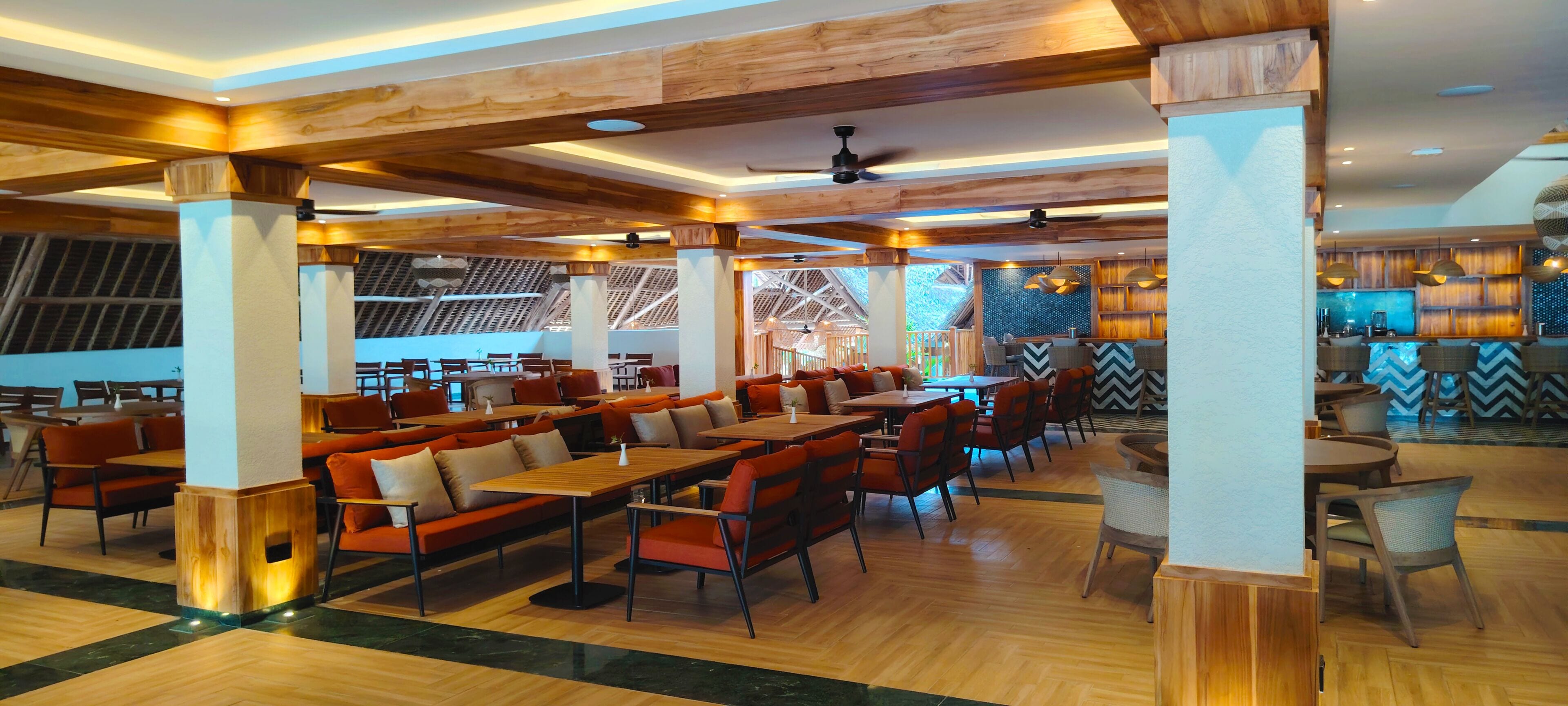 A spacious restaurant with wooden beams, high ceilings, and a mix of seating arrangements including tables and booths.