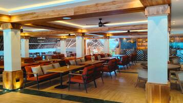 A spacious restaurant with wooden beams, high ceilings, and a mix of seating arrangements including tables and booths.