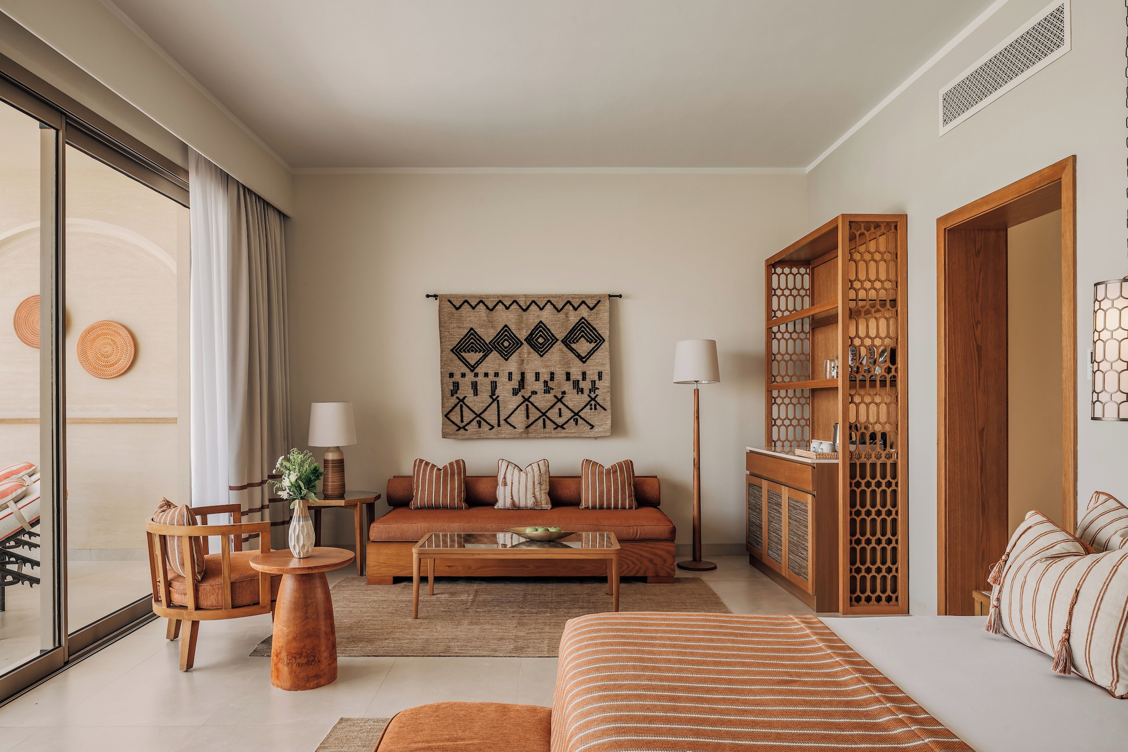 Een moderne hotelkamer met een bank, een salontafel, een bed en een groot raam met gordijnen.