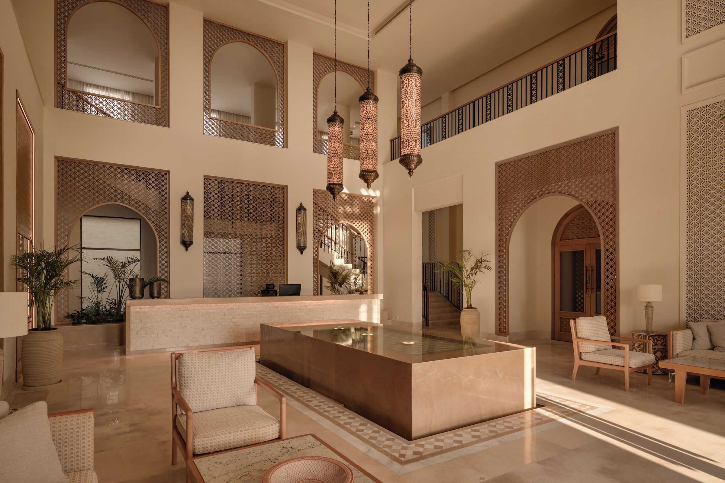 A spacious lobby with a central seating area, multiple arches, and hanging lanterns.