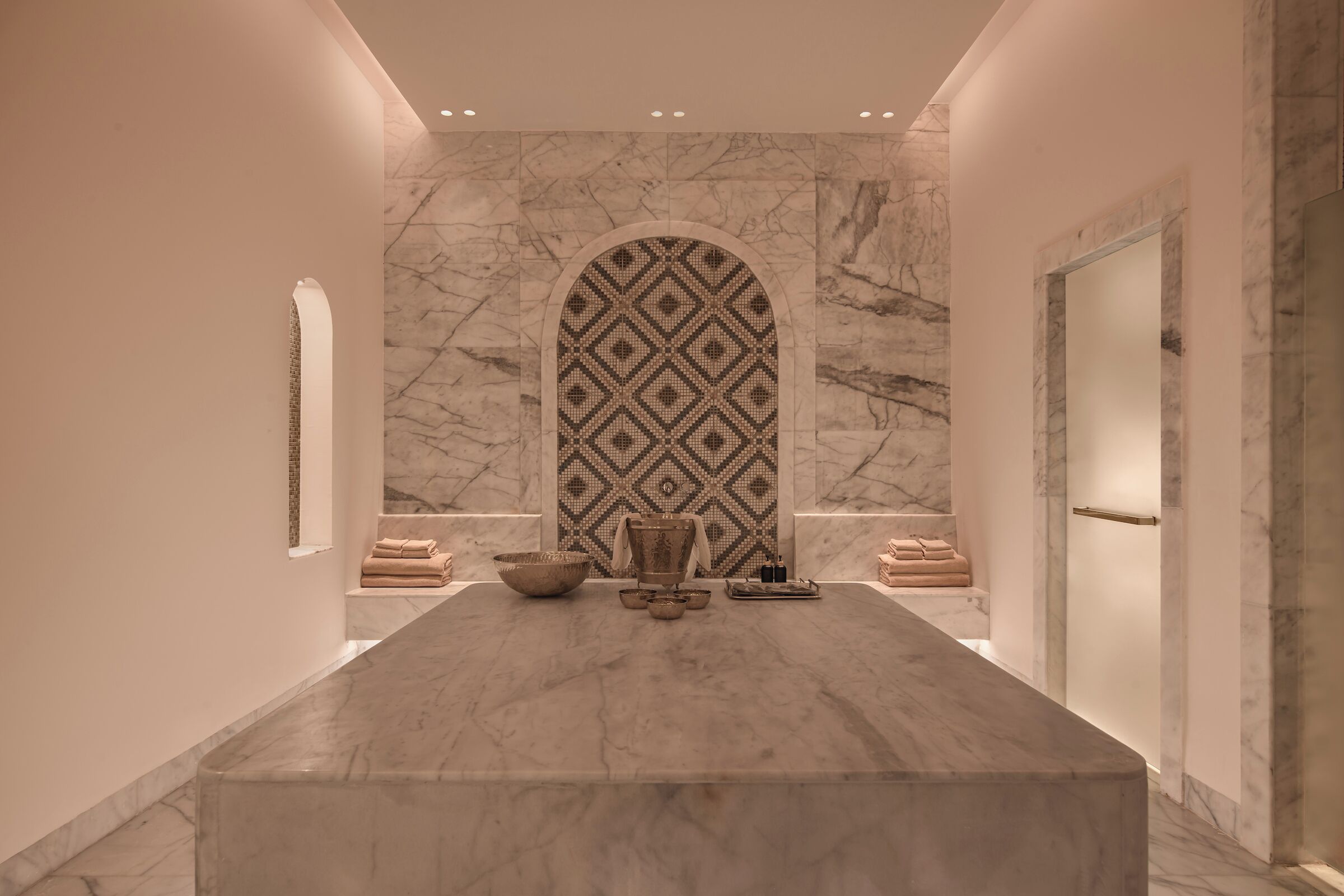 Une salle de bain moderne avec un meuble-lavabo en marbre, un mur orné d’un motif et un grand miroir.