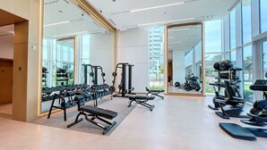 A modern gym with various exercise equipment, large windows, and a clean, spacious layout. - La Vie - Spacious One Bedroom (Jumeirah Beach Residence)