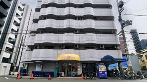 A multi-story building with a distinctive wavy facade, a visible storefront with signage, and a row of bicycles parked outside. - Grand Colbert NANBA 301, 303, 404, 602 (Osaka)