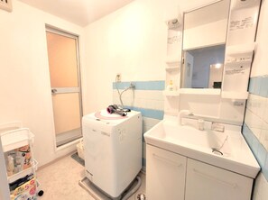 Ein kleines Badezimmer mit Waschmaschine, Waschbecken und Spiegel.