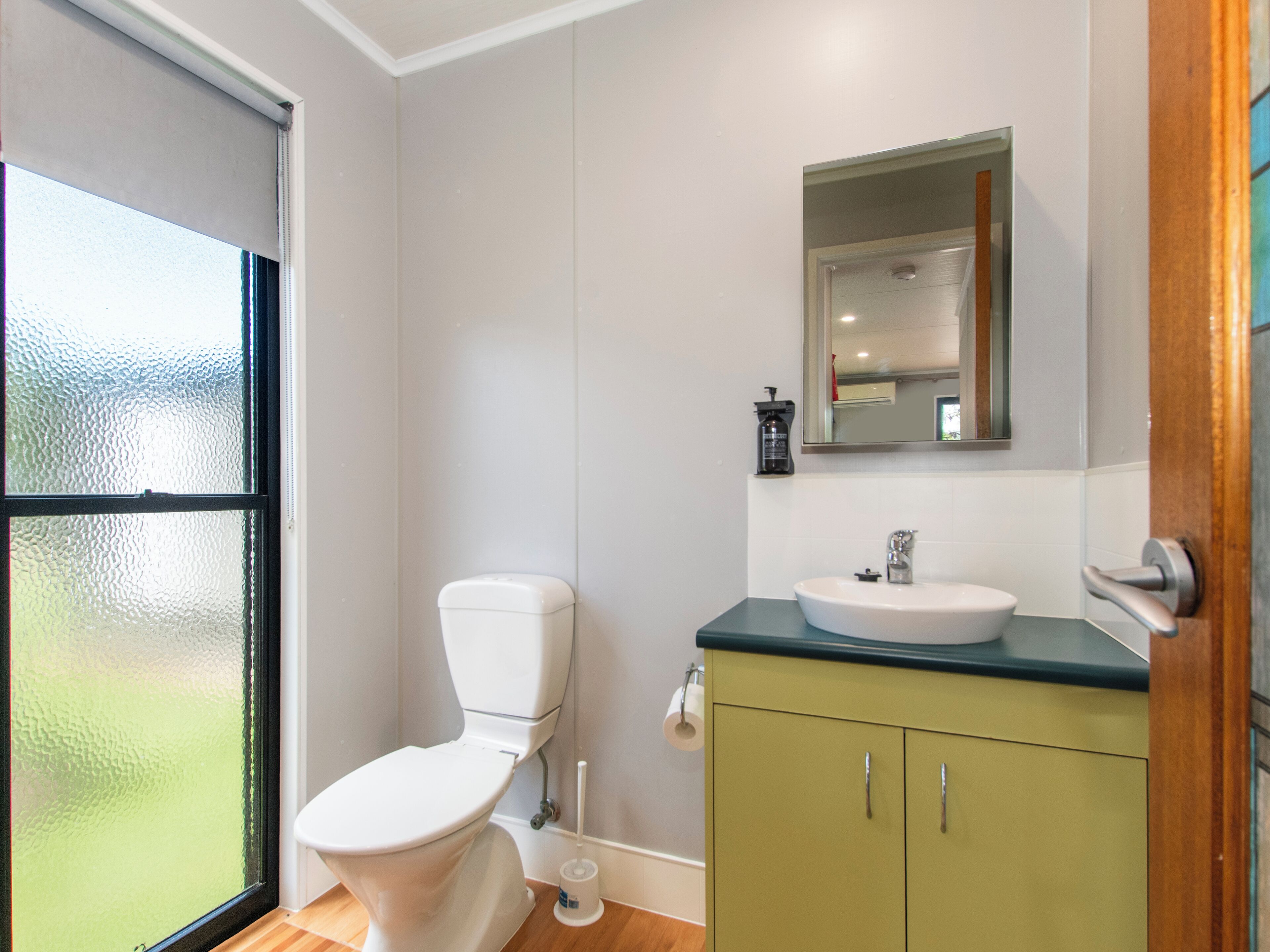 A bathroom with a toilet, sink, and mirror.