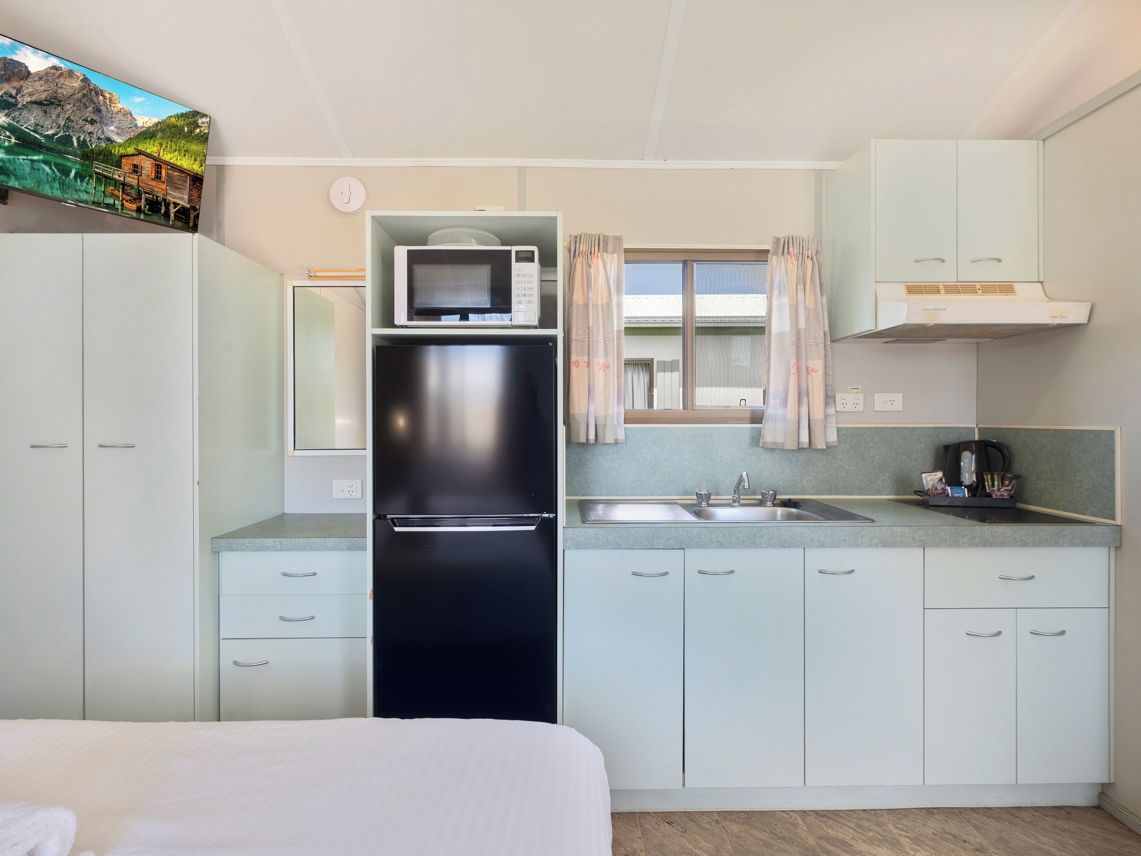 Cocina compacta con refrigerador, microondas y pileta.