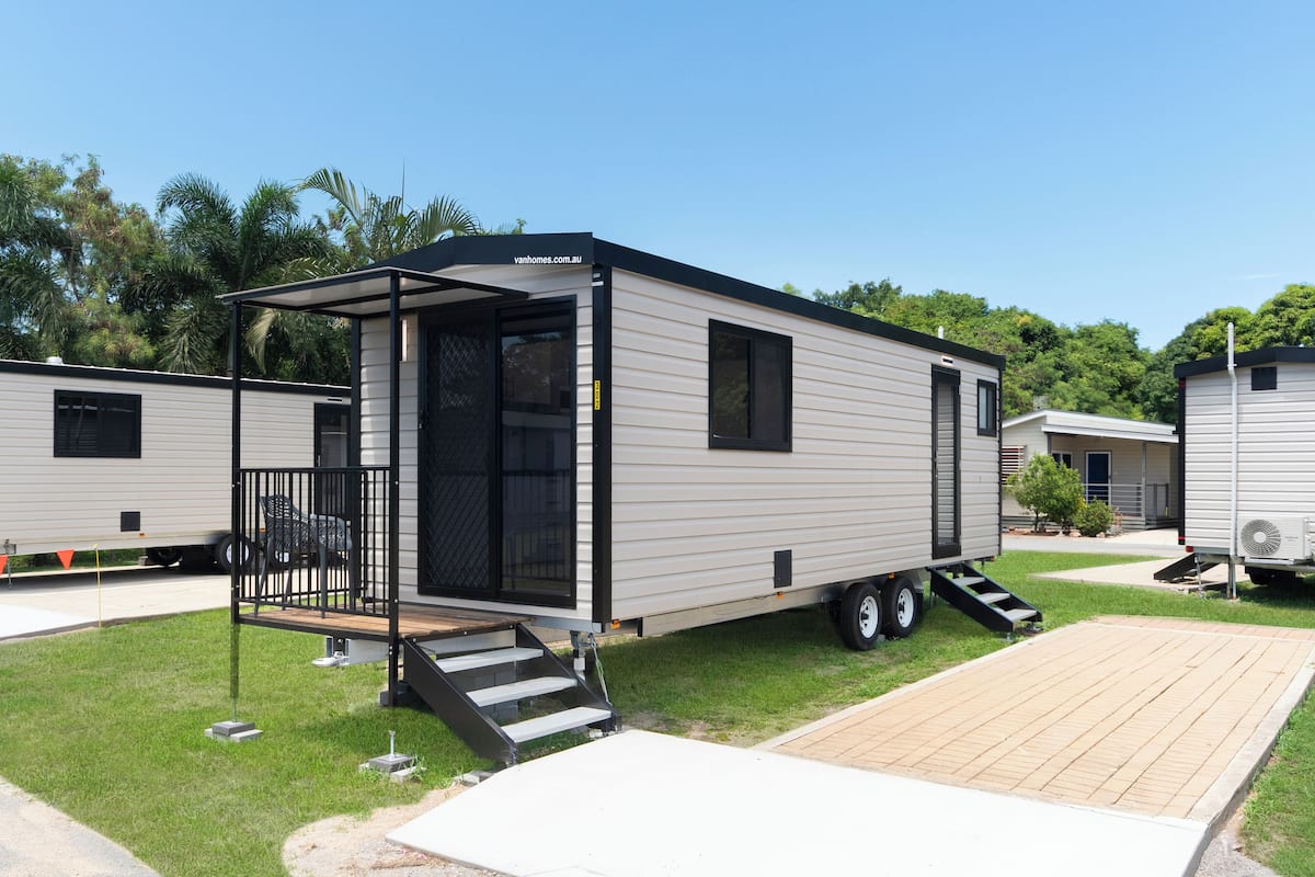A mobile home with a covered porch, a small deck, and a ramp leading to the entrance.