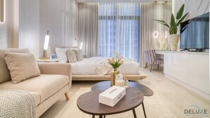 Une chambre d’hôtel moderne équipée d’un canapé, d’un lit, d’une table basse et d’un téléviseur.