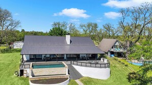 Ein modernes Haus mit Swimmingpool, überdachter Terrasse und einem gepflegten Rasen.