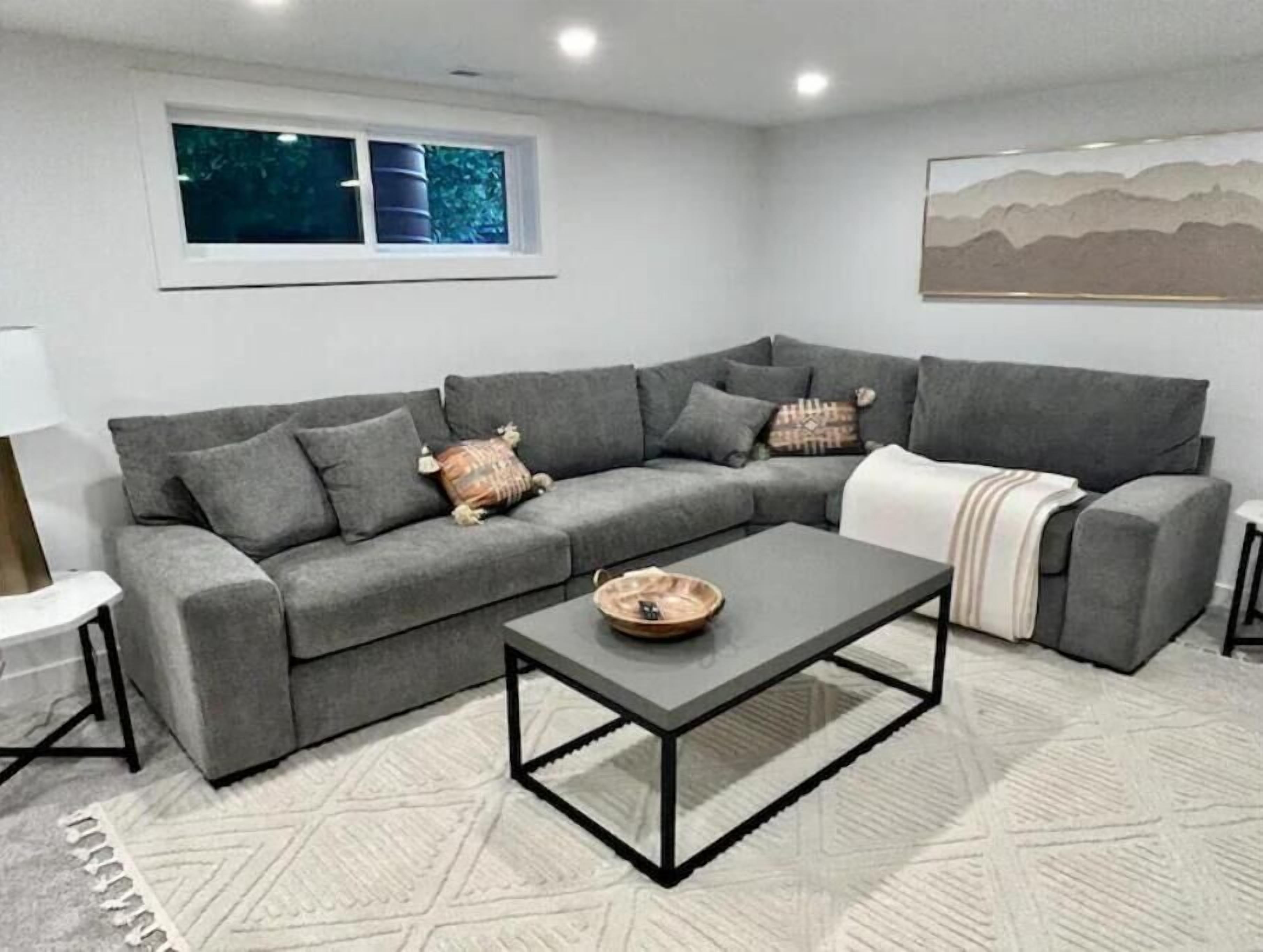 A modern living room with a grey sectional sofa, a coffee table, and a patterned rug.