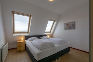 Relax in this serene bedroom with a large bed, bedside tables, and a unique artwork.