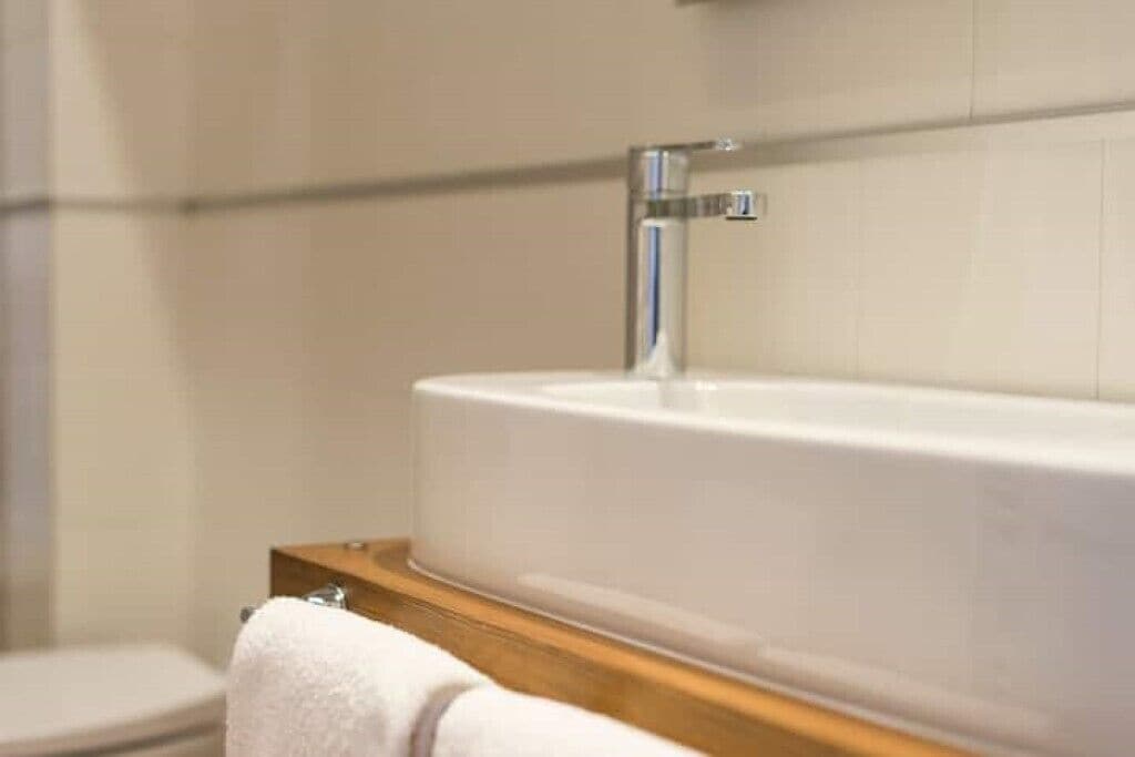 Et badeværelse med et hvidt badekar, en trækommode og et hvidt toilet.
