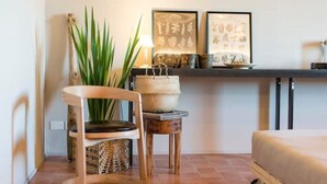 Una habitació acollidora amb una cadira de fusta, una taula petita, una planta en test i un sofà.