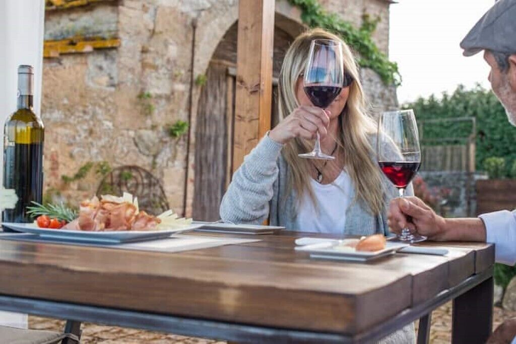 A dining table with a bottle of wine, a glass of red wine, and a plate of food.