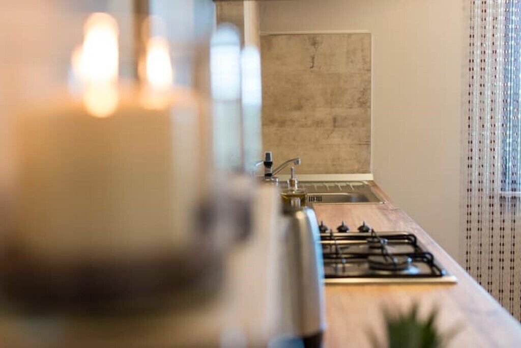 A kitchen with a gas stove, a sink, and a window with curtains.
