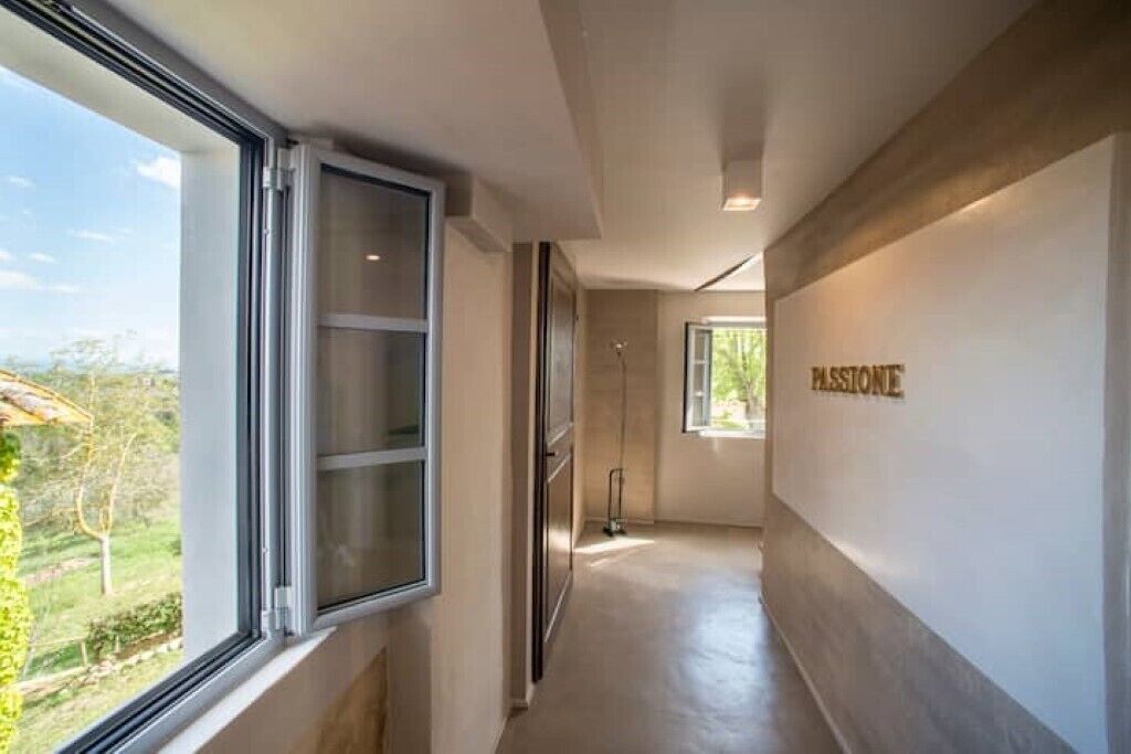 Ein moderner Flur mit einem großen Fenster, einem Mopp auf dem Boden und einer Wand mit dem Schriftzug "PASSIONE".