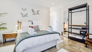 Une chambre moderne avec un grand lit, une table de chevet, une commode, un miroir et une bibliothèque intégrée.