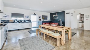 Une cuisine moderne avec des meubles blancs, une table à manger en bois avec des bancs, et un mur noir orné du texte « Atlantic 62 ».