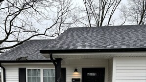 A single-story house with a black door and white siding.