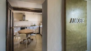 A modern kitchen with white cabinets, a wooden dining table, and a large gold sign that reads "AMORE". - Immersed in the silence of the Tuscan countryside, the Superior apartment offers an unspoiled view of the Tuscan countryside.Equipped with a kitchenette, living room, private bathroom and 2 bedrooms, 1 double bed and 1 queen bed, it offers: stove, refrig (Siena)