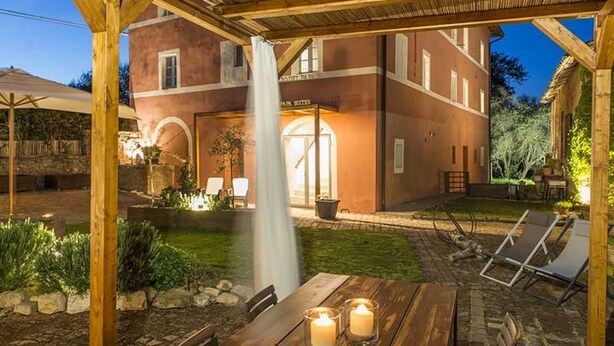 A patio area with a wooden pergola, a table with candles, and a building with a sign that reads "Park Suites". - Immersed in the silence of the Tuscan countryside, the Superior apartment offers an unspoiled view of the Tuscan countryside.Equipped with a kitchenette, living room, private bathroom and 2 bedrooms, 1 double bed and 1 queen bed, it offers: stove, refrig (Siena)