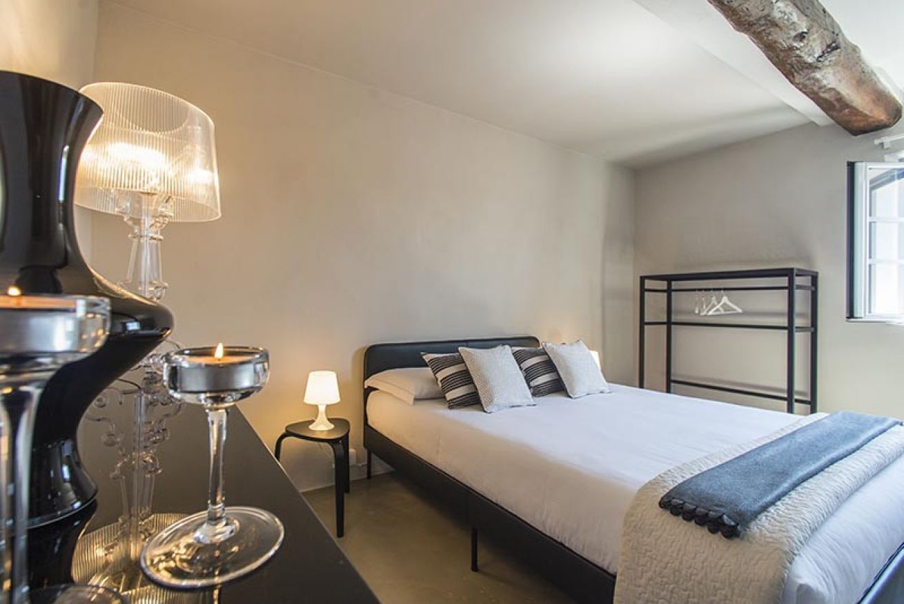 A bedroom with a bed, bedside tables, a lamp, and a window.