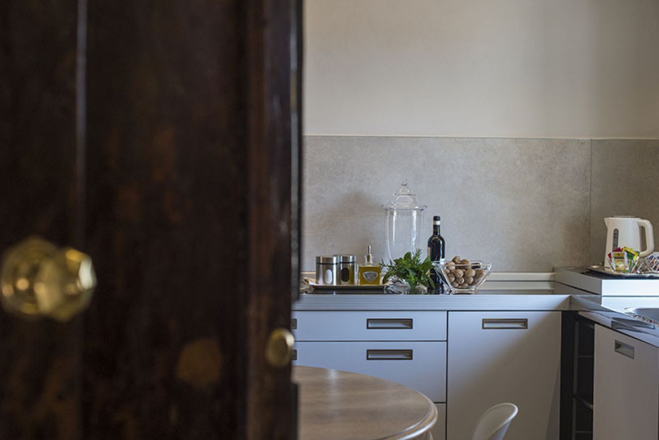 A kitchen with a round table, cabinets, and a countertop with various items.