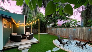 A backyard with a wooden deck, outdoor seating, and a decorative string of lights.