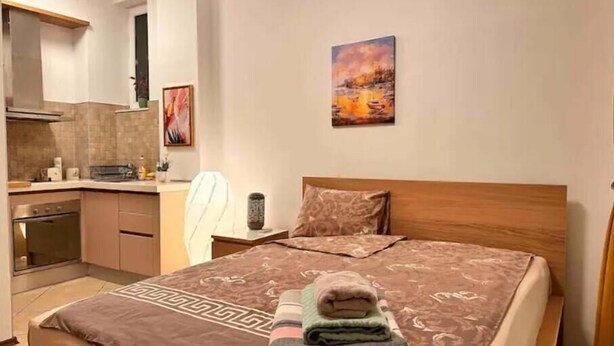 Une chambre à coucher avec un lit, une table de chevet, une commode et un tableau accroché au mur.