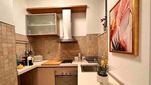 Une cuisine de taille réduite, équipée d’une cuisinière, d’un four, d’un évier et d’un petit plan de travail.
