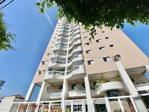 A multi-story building with balconies, large windows, and a clear sky.