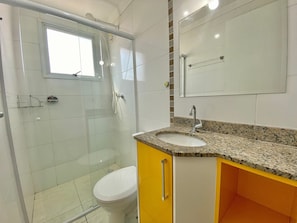 A bathroom with a shower, toilet, sink, and mirror.