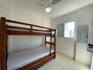 A bunk bed in a room with a ceiling fan, a window with blinds, and a mirror on the wall.
