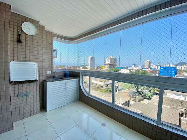 A balcony with a view of a cityscape, a clock on the wall, and a tiled floor.