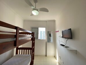 A room with a bunk bed, a ceiling fan, a television mounted on the wall, and a window with blinds. - Residencial Octávio Braga (Praia Grande)