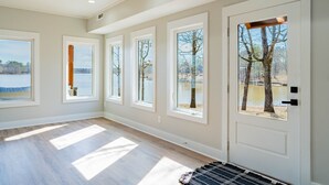 Una habitación amplia con ventanas grandes, una puerta con vistas y piso de tonos claros.