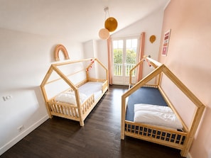 A room with two wooden bunk beds, a window with curtains, and a door leading outside. - Magnifique Maison Moderne à Bidart - 15min à Pieds du Centre et de la Plage (Bidart)