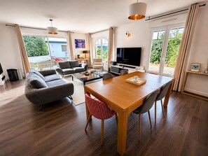 A modern living room with a sofa, TV, dining table, and large windows. - Magnifique Maison Moderne à Bidart - 15min à Pieds du Centre et de la Plage (Bidart)