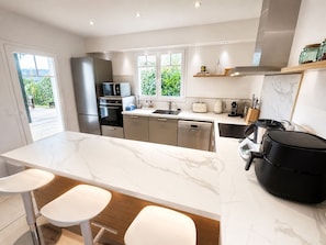 Una cocina moderna con electrodomésticos de acero inoxidable, encimera de mármol y una isla grande con taburetes de bar.