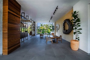 A modern interior with a dining area, a wooden wall, and a large potted plant.