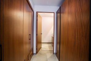 A hallway with wooden doors leading to a room with a tiled floor. - Two Pools, Bar & Gym | Casa Medianoche at Oasis (Puerto Vallarta)